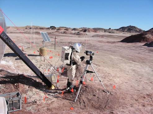 A simulated Mars landscape with Dusty serving as a Mars explorer with his research equipment including a set of dipole antennas.